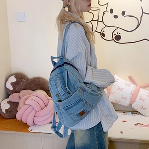 Washed denim backpack for women with flap pocket and vintage aesthetic worn by model