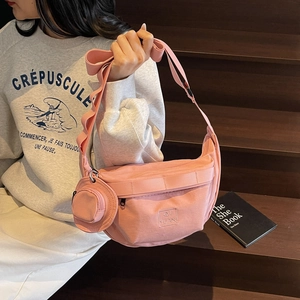 Sac bandoulière en toile rose en forme de croissant avec pochette ronde sur le mannequin