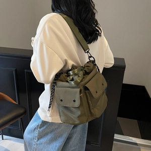 Olive green utility drawstring bucket bag with multiple pockets worn by a model