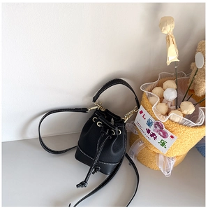Detail of black mini bucket bag with white contrast stitching and gold metal buckles