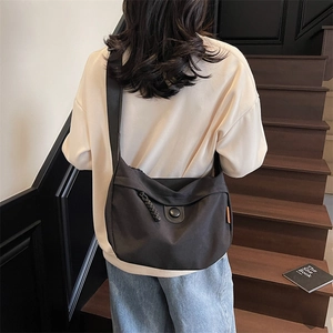 Minimalist black canvas crescent crossbody bag with braided zip puller and flap closure