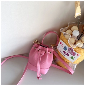 Detail of pink mini bucket bag with litchi texture, drawstring and gold eyelets