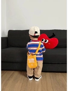 Dettaglio della borsa a tracolla bimbi gialla in tela con t-shirt a righe blu e rosse