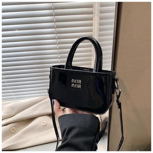 Dettaglio mini borsa in pelle verniciata nera lucida con elementi in metallo argentato