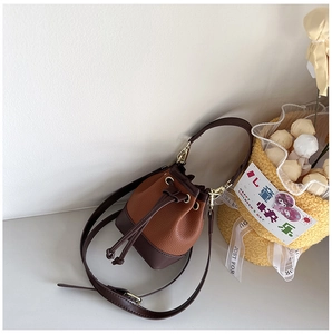 Close-up of brown patchwork leather bucket bag with drawstring and golden hardware