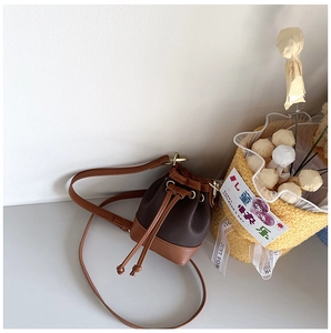 Detail of a brown leather bucket bag for kids with drawstring closure and shoulder strap