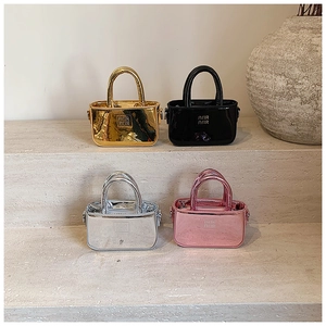 Mini borse metalliche per bambine in oro, nero, argento e rosa su gradini di pietra