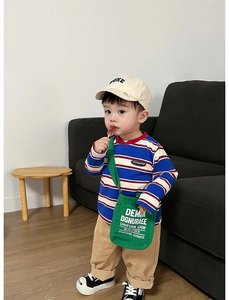 Dettaglio della borsa a tracolla in tela verde e t-shirt a righe a maniche lunghe bimbo