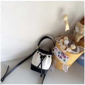 Close-up of mini black and white bucket bag with drawstring and metal hardware detail