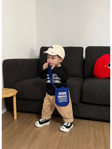 Borsa a tracolla in tela blu per bambini con scritte abbinata a un outfit casual da ragazzo