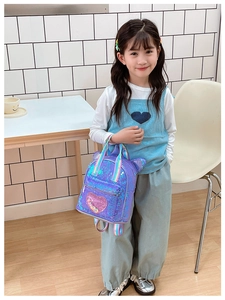Detail of sequin heart pocket and rainbow straps on a purple glitter kids backpack