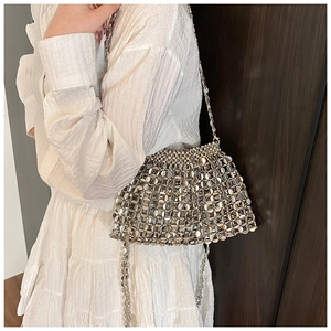 Close-up of a silver metallic sequin beaded handbag worn with a white textured dress