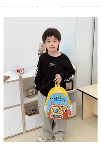 Enfant portant un sac à dos jaune avec broderie de pelleteuse dans un décor intérieur