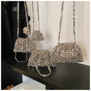 Multiple sizes of silver sequin woven handbags shown against a black blazer and wood table