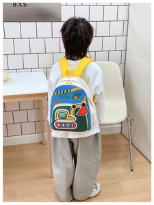 Vue arrière d'un enfant portant un sac à dos en toile blanche avec écusson pelleteuse