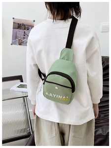 Detail of light green nylon crossbody bag with adjustable strap and front zipper pocket