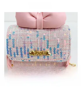 Close-up of pink tweed girl's crossbody bag with bow detail and golden heart buckle
