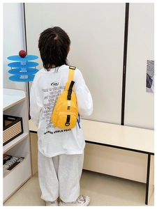 Detail of yellow nylon kids chest bag with KAYI NAI letters and adjustable black strap
