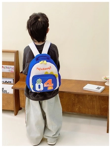 Detailansicht eines leichten Kinderrucksacks mit Cartoon-Dinosaurier in Blau-Gelb-Weiß-Design