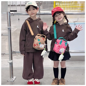 Detailed close-up of a child's crossbody bag with heart pattern and matching brown hoodie