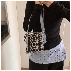 Détail du sac seau noir à cordon avec cage métallique en perles argentées et chaîne