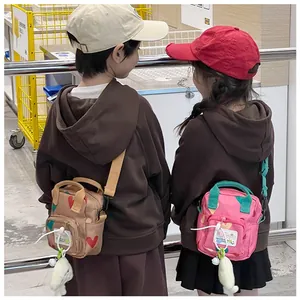 Kids heart print crossbody bags with plush charms shown on young models in a lifestyle setting