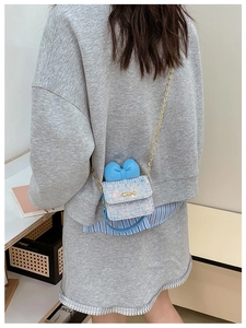 Detail of light blue tweed mini crossbody bag with leather bow and gold chain on model