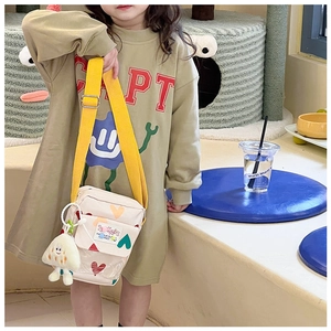 Detail of cream kids crossbody bag with heart patterns and plush charm on adjustable strap