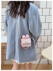 Close-up of pink lace shoulder bag featuring a 3D bow and golden chain strap