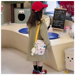 Rear view of a child wearing a beige heart pattern canvas crossbody bag with toy charm