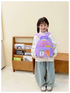 Nahaufnahme lila Kinderrucksack mit grünem Dino-Cartoon und Baseball-Stickerei