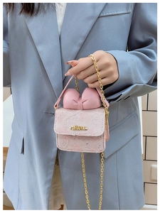 Close-up of pink lace mini bag featuring a large leather bow and gold chain strap