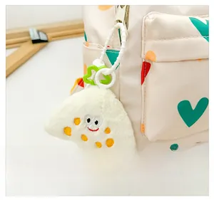 Détail d'un sac à dos à motif de cœurs avec un charm en peluche et une fermeture éclair