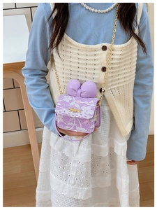 Detail of girl's mini purple crossbody bag with floral lace and a large bow