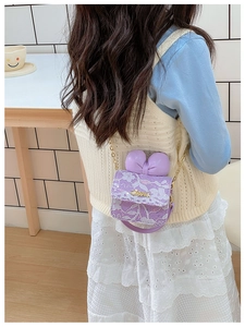 Detail of purple lace embroidery girl's crossbody bag with bow and golden chain