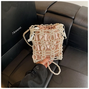 Détail du sac seau en perles blanches avec doublure en satin rose et cordon de serrage