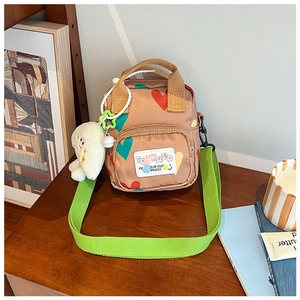 Detail of canvas crossbody bag with heart prints, green strap, and cloud plush charm