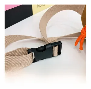 Détail de la sangle en nylon kaki avec boucle noire et cordon décoratif orange vif