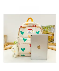Sac à dos enfant à motifs cœurs blanc cassé avec iPad pour comparer la taille