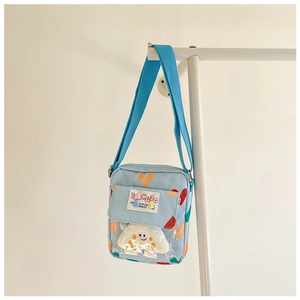 Detail of light blue canvas crossbody bag for kids with colorful heart patterns and PVC pocket