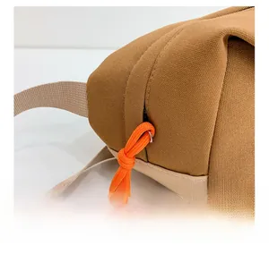 Détail du sac de poitrine en toile kaki avec cordon de zip orange et boucle de sangle robuste