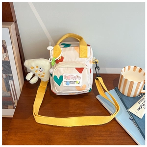 Close-up of cream canvas kids crossbody bag with heart prints and yellow strap