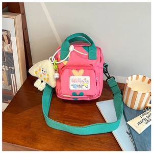 Pink kids crossbody bag with heart prints and green strap detail and charm