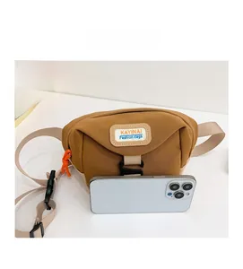 Sac de poitrine en toile marron avec étiquette et zip orange à côté d'un smartphone blanc