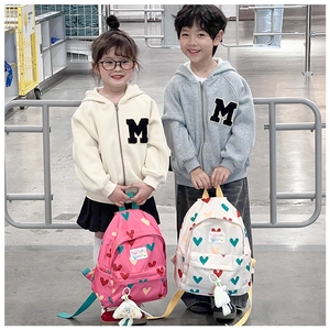 Détail de sacs à dos pour enfants rose et beige avec motifs de cœurs et porte-clés peluche