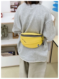 Détail d'un sac banane de sport jaune vif avec logo noir porté par un mannequin