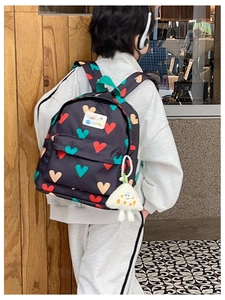 Détail du sac à dos enfant à motif cœur avec un pendentif en peluche triangulaire