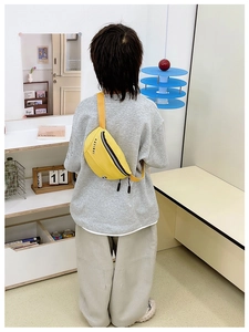 Détail d'un sac bandoulière enfant jaune vif avec fermeture éclair noire et logo