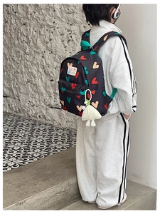 Vue détaillée d'un sac à dos pour enfant avec motifs cœurs colorés et breloque poupée