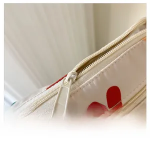 Détail de la fermeture éclair fluide sur le sac à bandoulière en toile à motifs cœurs